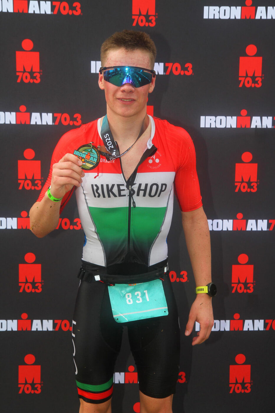 Sigurd holding up a finisher medal after an IRONMAN 70.3 race