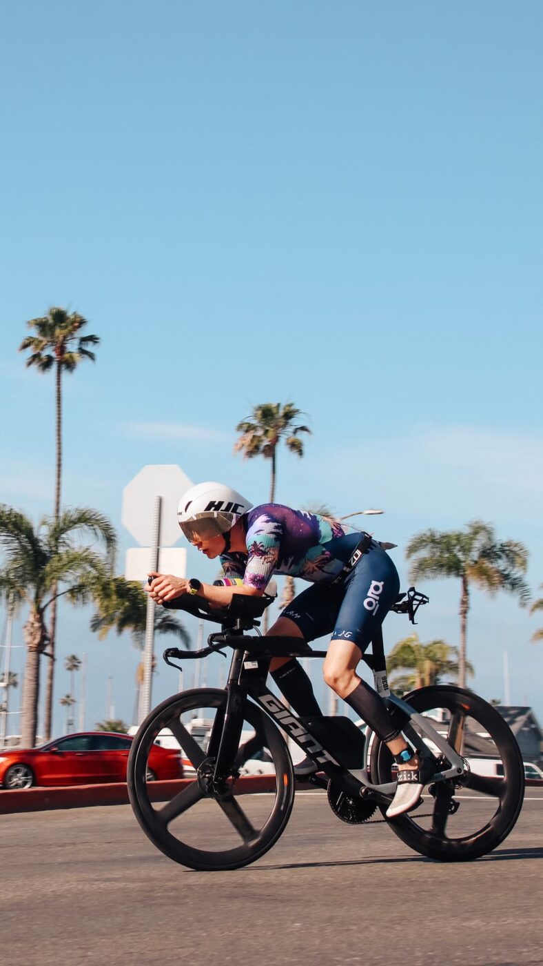Sigurd riding his time-trial bike in an aero position on a race course lined with palm trees